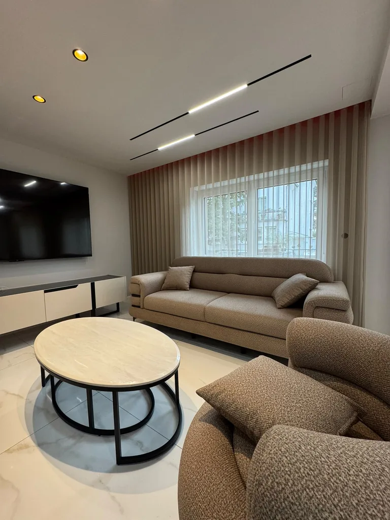 Bodenlange beige Wellengardinen hinter dem Sofa mit Blick auf die Fernseherwand