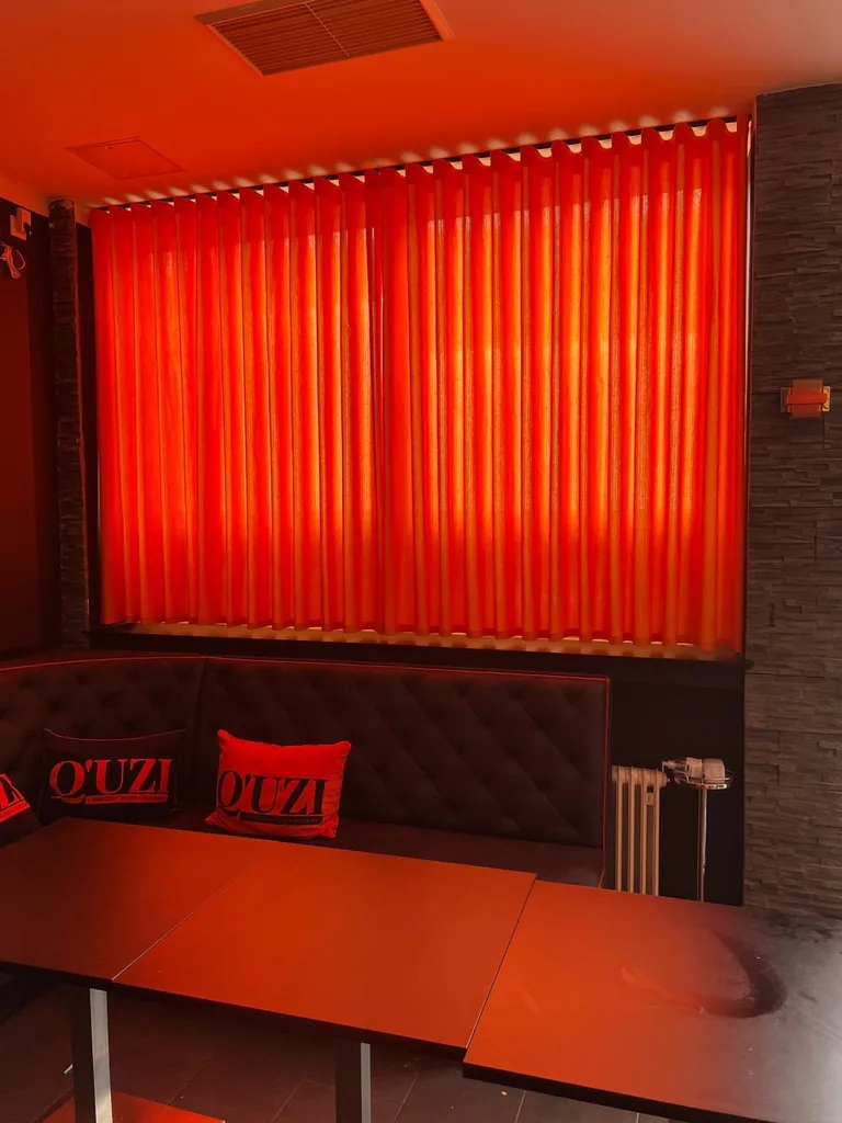 Geschlossene orangefarbene Wellenvorhänge über einer schwarzen Sitzbank in einer Lounge