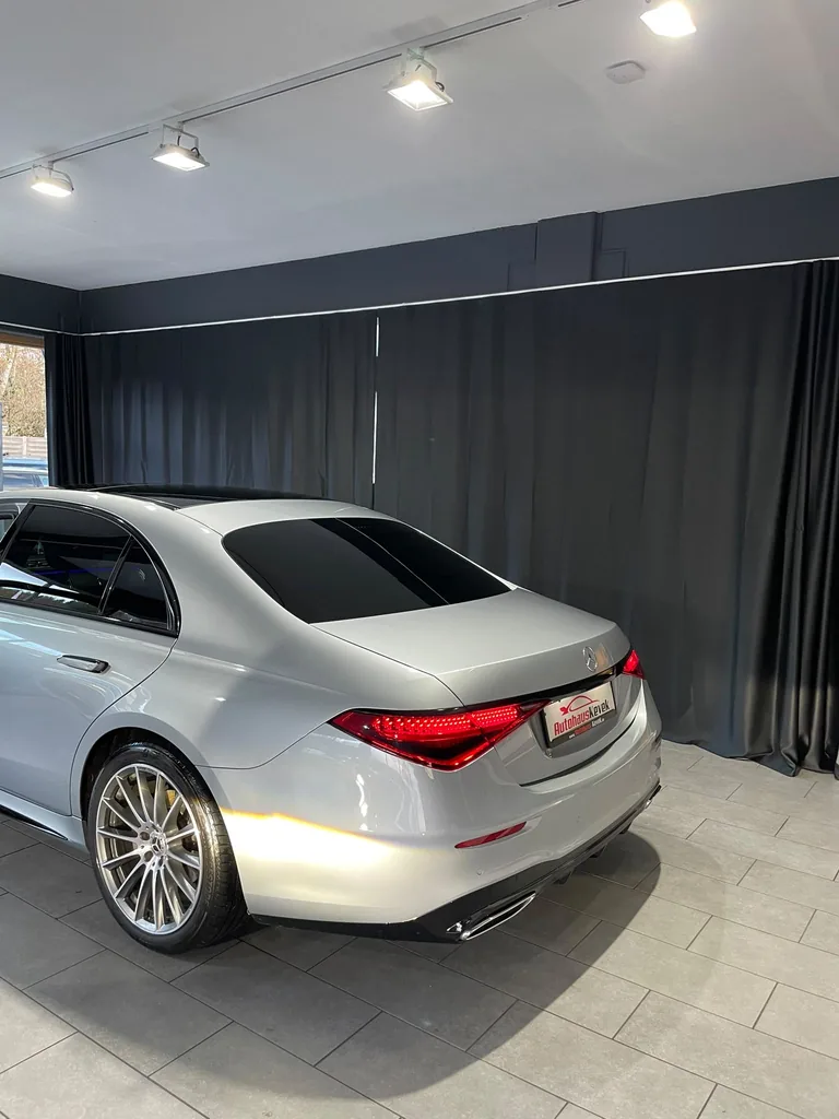Geschlossene dunkelgraue Vorhänge hinter einem silberfarbenen Fahrzeug im Autohaus